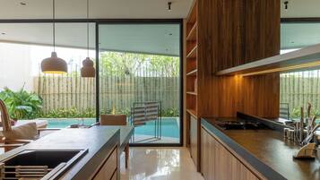 A modern kitchen with a large island, wooden cabinets, and a view of a swimming pool.