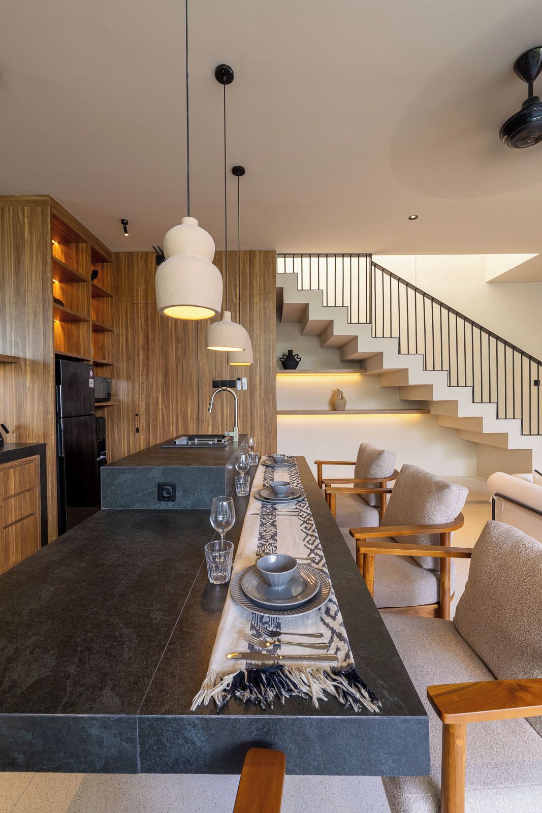 Una cocina moderna con una isla central, muebles de madera e iluminación colgante.