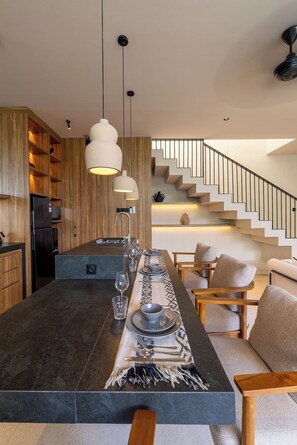 Una cocina moderna con una isla central, muebles de madera e iluminación colgante.