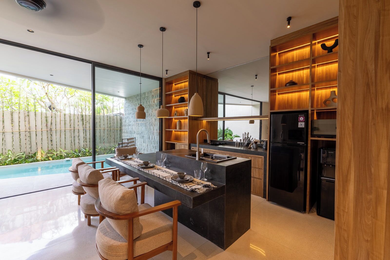 Una cocina moderna con una isla central, asientos tipo barra y vista a una piscina.