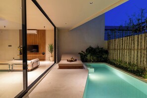 A modern outdoor living space with a pool, seating area, and a view of the night sky. - Sila Villa Berawa - By Saamu (Badung)