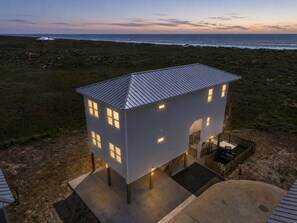 A modern house with a flat roof, multiple windows, and a small porch area.