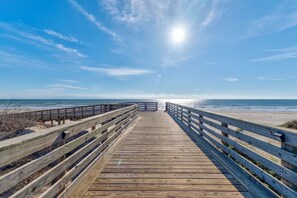 A wooden boardwalk leading to a beach with a clear sky and sun shining. - New! Front row!Beachfront! Private Pool (Port Aransas)