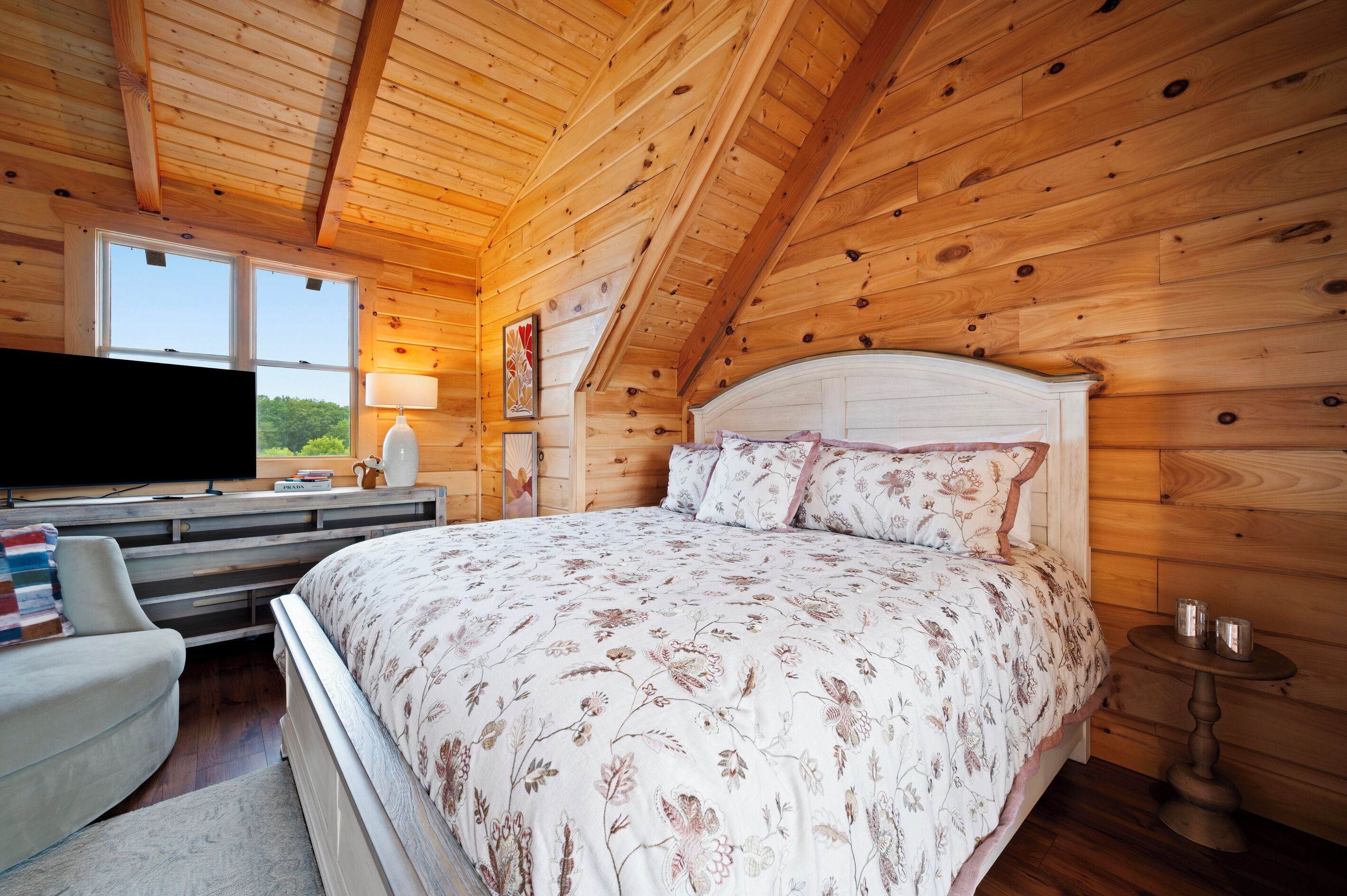 A wooden room with a bed, a TV, and a window.