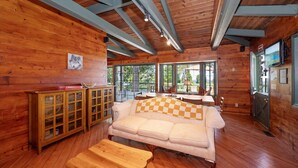 Interior acogedor de una cabaña con piso de madera, un sofá, un armario de madera y un televisor.