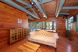 Ein gemütliches Blockhaushaus-Interieur mit Holzboden, einer Couch, einem Holzschrank und einem Fernseher.