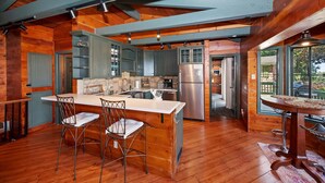Una cocina amplia con una isla central, piso de madera y una pared de acento de piedra.