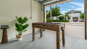 A foosball table in a garage with a view of a residential street. - Designer Pool Home • Near Las Olas • Sleeps 10 (Fort Lauderdale)