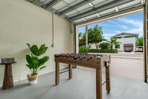 A foosball table in a garage with a view of a residential street. - Designer Pool Home • Near Las Olas • Sleeps 10 (Fort Lauderdale)