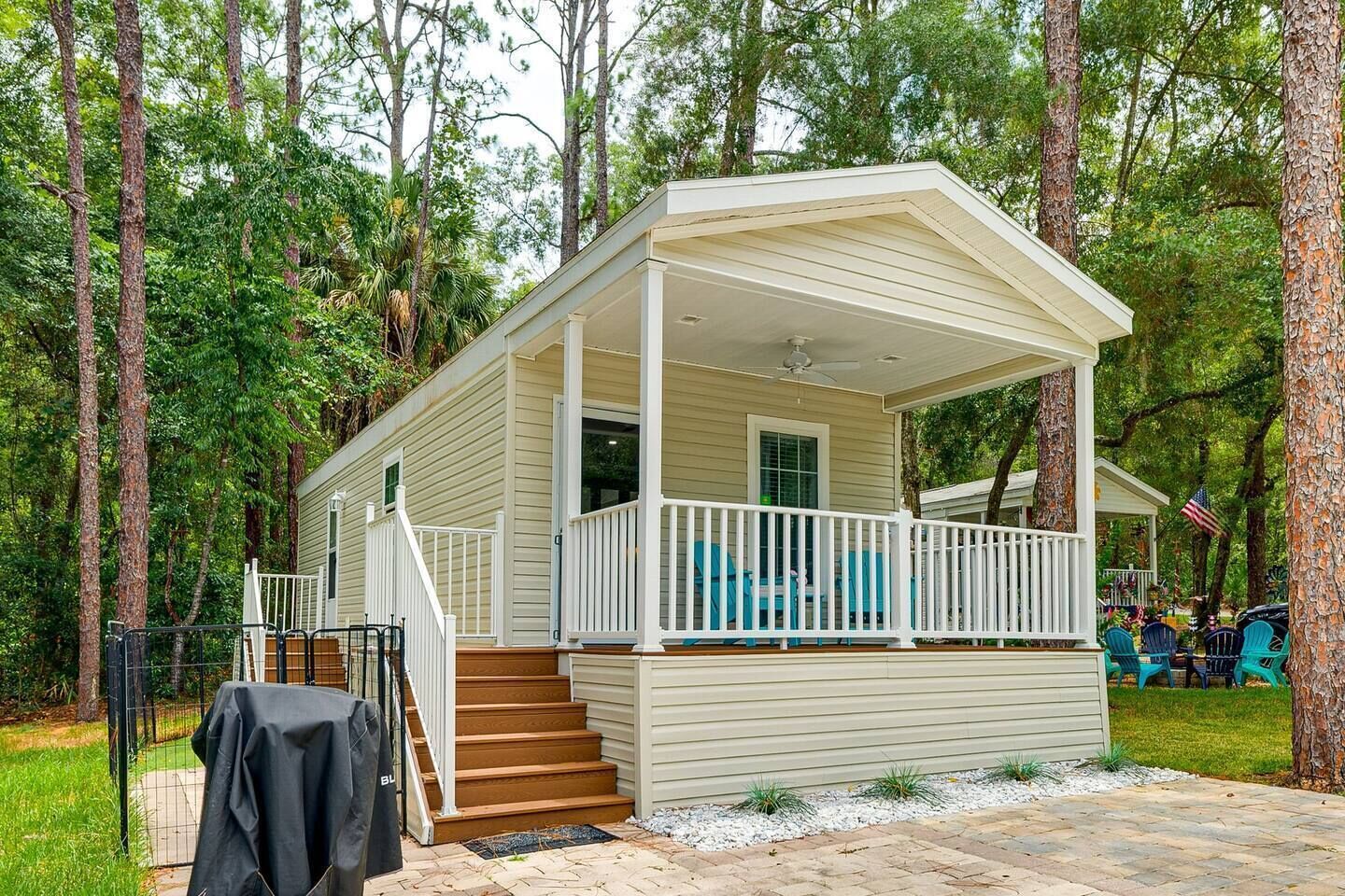 A single-story cabin with a covered porch, a set of stairs leading to the entrance, and a small outdoor seating area.