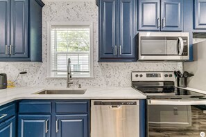A kitchen with blue cabinets, a microwave, an oven, and a dishwasher. - New Crystal River Resort Cabin w/Pool & Boat Prkng (Crystal River)