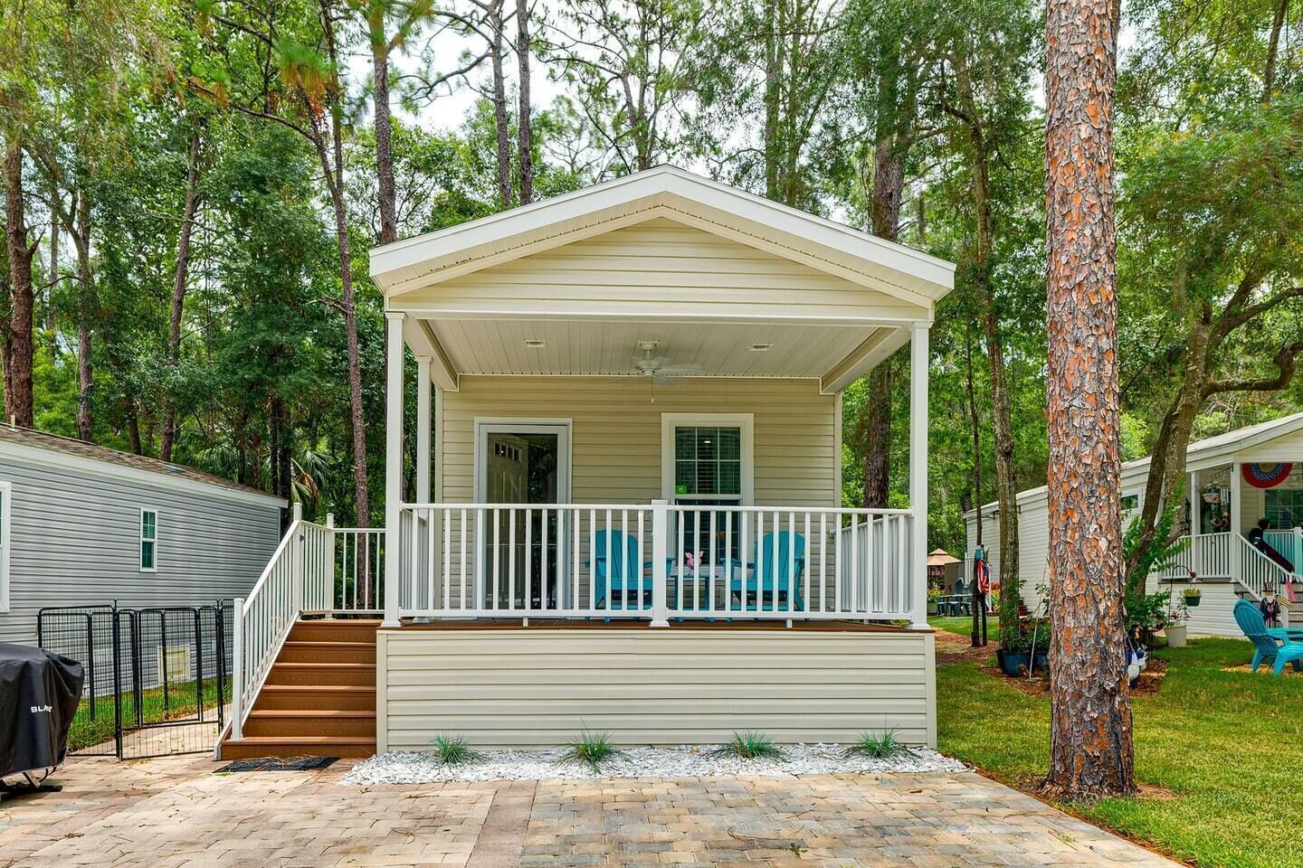 A single-story mobile home with a covered porch, a small front entrance, and a brick pathway leading to the entrance.