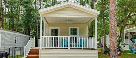 A single-story mobile home with a covered porch, a small front entrance, and a brick pathway leading to the entrance.