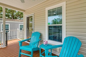 A covered porch with two turquoise Adirondack chairs and a small table, overlooking a residential area. - New Crystal River Resort Cabin w/Pool & Boat Prkng (Crystal River)