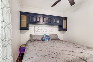 Ein Schlafzimmer mit einem Bett, einem Kopfende mit eingebauten Schränken und einem an der Wand befestigten Schild.