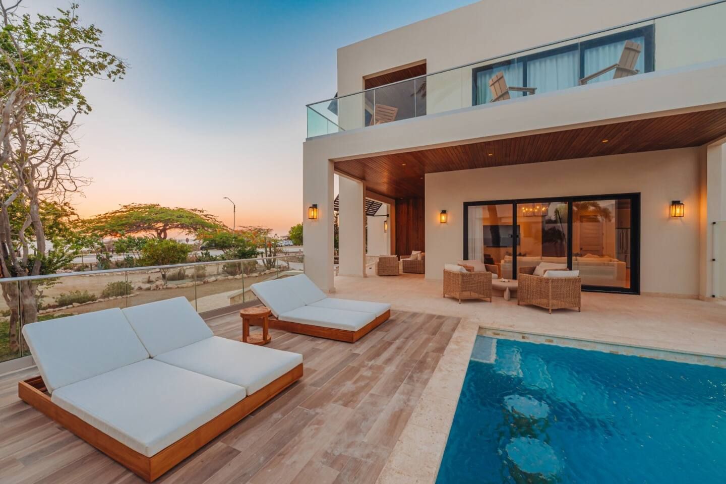 Un hotel moderno con zona de piscina, sillas de descanso y vistas al atardecer.
