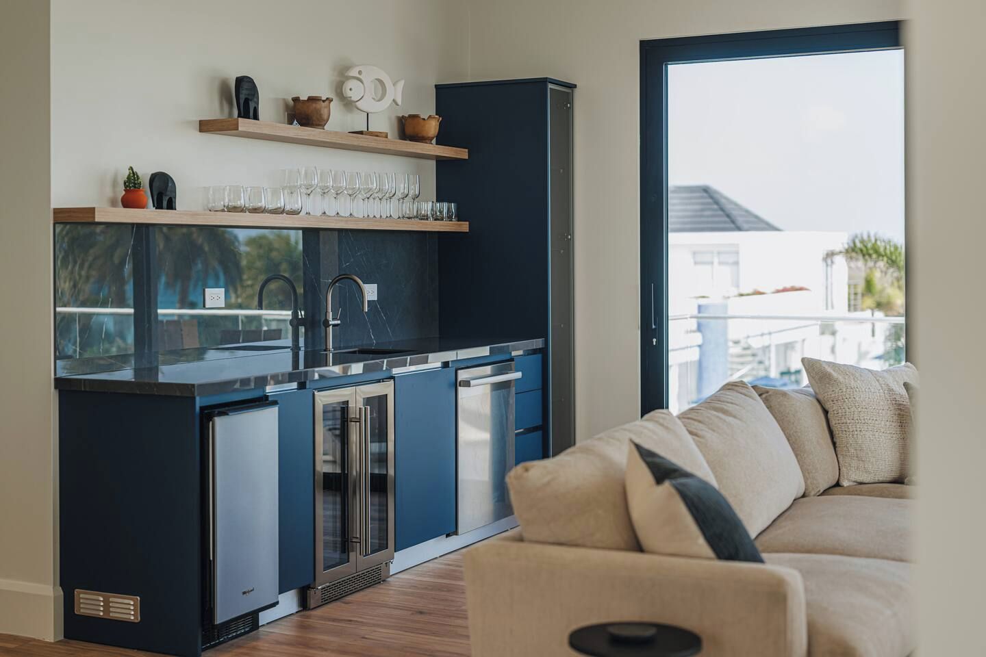 Eine moderne Küche mit Einbaugeräten, ein Essbereich mit einer Couch und Blick ins Freie.