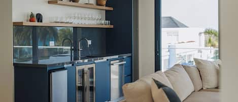 Et moderne køkken med indbyggede apparater, et spiseområde med en sofa og udsigt til det fri.