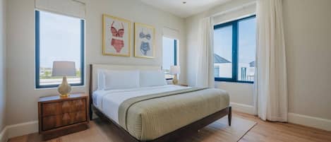 A bedroom with a bed, two bedside tables, and a window with curtains.