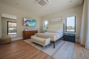 Ein Schlafzimmer mit einem Bett, einem Nachttisch, einer Bank, einem großen Fenster und einem Gemälde an der Wand.