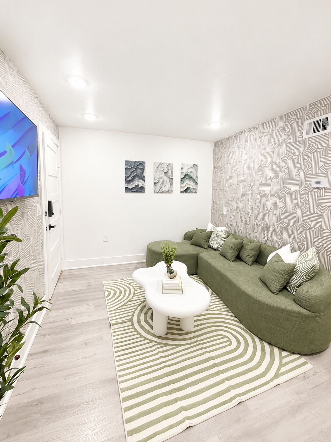 A modern living room with a sectional sofa, a white coffee table, and a patterned rug.