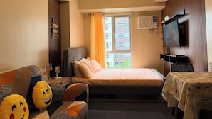 Een hotelkamer met een bed, een slaapbank, een televisie en een tafel met tafelkleed.