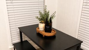 Ein schwarzer Tisch mit Kerze und Topfpflanze auf einem Holzteller.