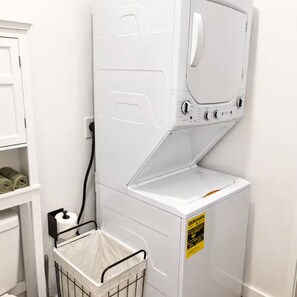 A white laundry room with a washing machine, a dryer, and a metal laundry basket. - Luxury Cozy  1-bedroom house in Quitman with AC (Quitman)
