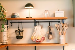 A kitchen shelf with a coffee mug rack, hanging kitchen utensils, and a lamp. - The Salty Manatee Near 3 sister springs (Crystal River)