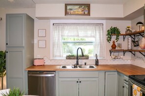 Une cuisine avec une fenêtre, un évier, un grille-pain et un lave-vaisselle.