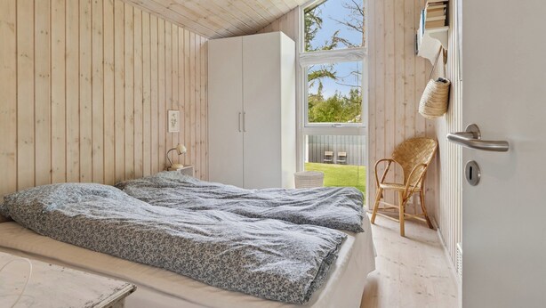 A bedroom with a bed, a chair, a wardrobe, and a window. - Lovely holiday home with great view (Græsted)