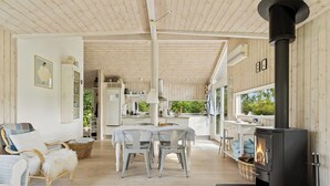 A cozy interior with a dining area, a fireplace, and a kitchen visible through an open door. - Lovely holiday home with great view (Græsted)