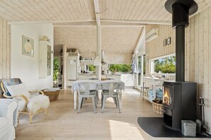 Ein gemütliches Interieur mit Essbereich, Kamin und durchgehender Tür erkennbarer Küche.