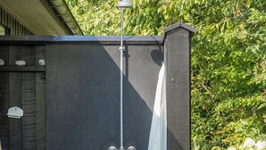 A black metal gate with a white curtain, a metal pole, and a wooden structure with a metal roof. - Lovely holiday home with great view (Græsted)