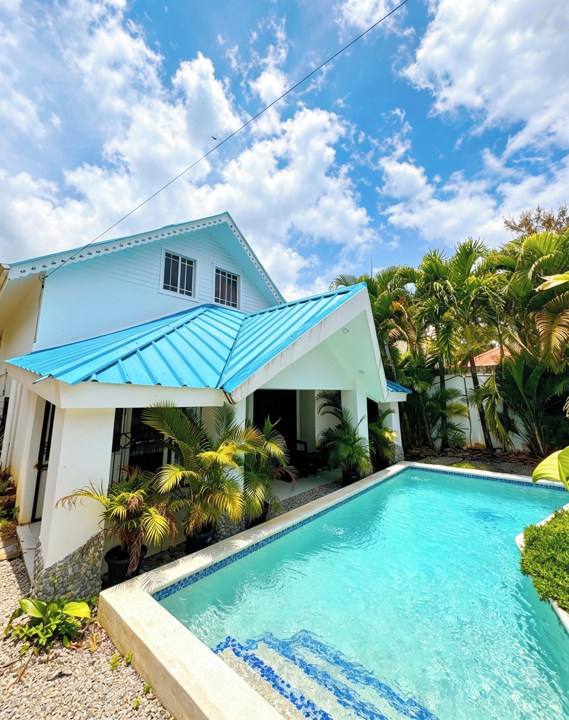 A house with a swimming pool, surrounded by tropical plants.