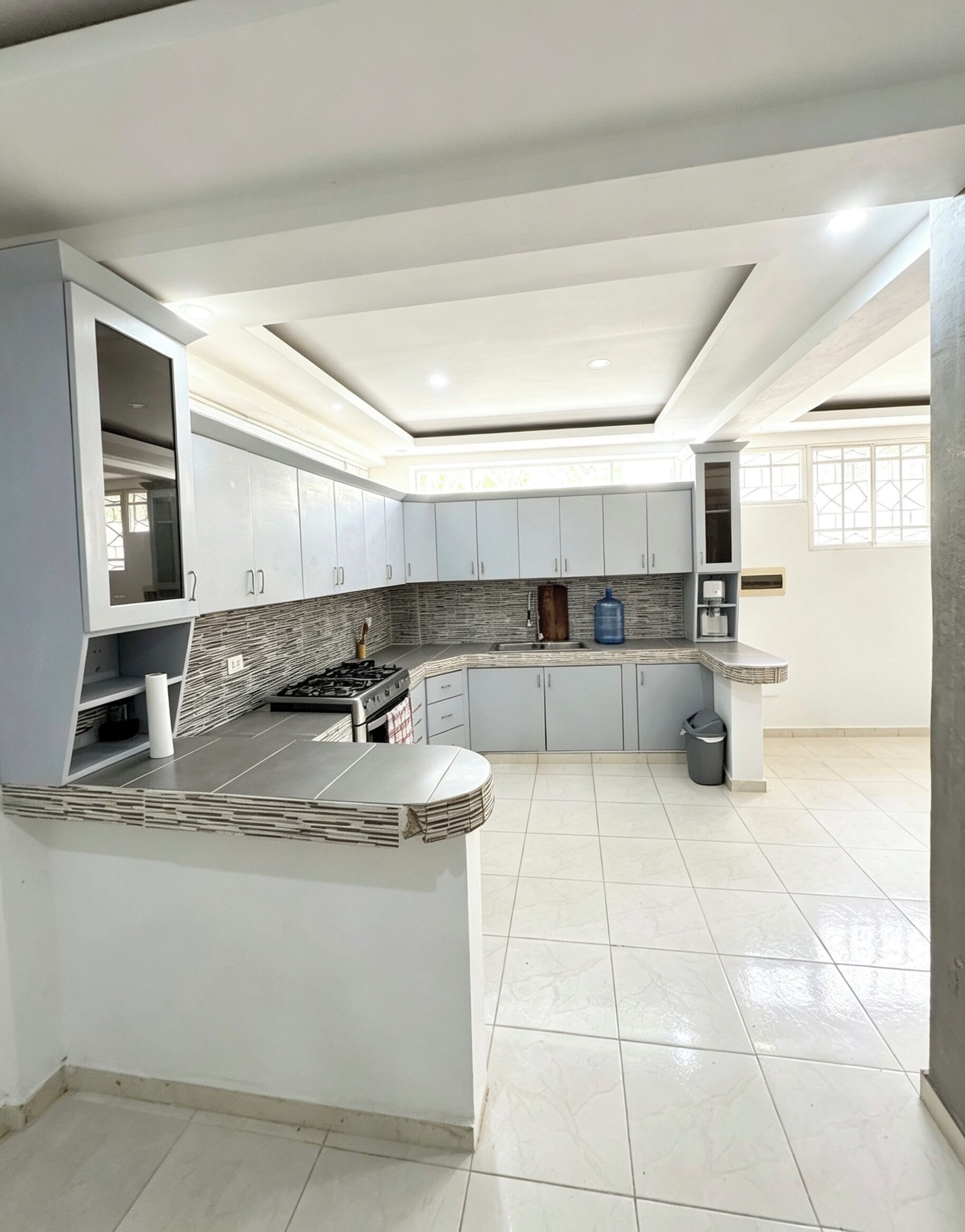 A modern kitchen with white cabinets, a central island, and a tiled backsplash.