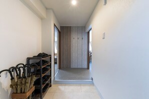 A hallway with a shoe rack, a door leading to another room, and a light switch on the wall. - June 2025 open! 3LDK/ Center of Shinsaibashi, Go Namba! (大阪市西区北堀江１丁目)