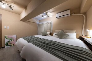 A hotel room with a large bed, a bedside table with a lamp, an air conditioning unit, and a painting on the wall. - June 2025 open! 3LDK/ Center of Shinsaibashi, Go Namba! (大阪市西区北堀江１丁目)