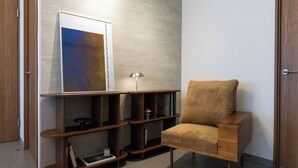 Een moderne kamer met een houten stoel, een boekenkast en een lijst met abstracte kunst.