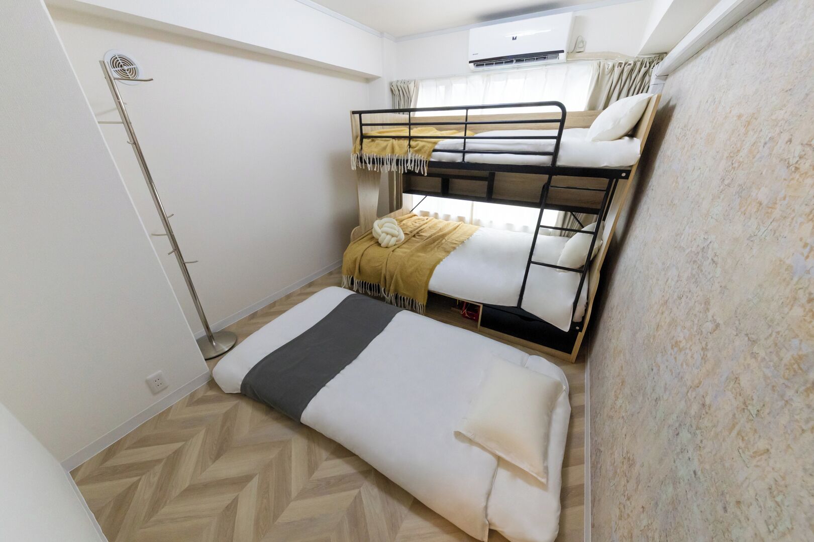 Habitación pequeña con literas, una cama individual, calentador y aire acondicionado.