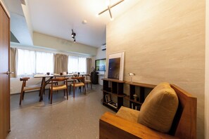 A modern living room with a dining area, wooden furniture, a flat-screen TV, and a large window with curtains. - June 2025 open! 3LDK/ Center of Shinsaibashi, Go Namba! (大阪市西区北堀江１丁目)