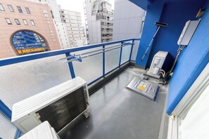 A balcony with a blue railing, a white air conditioning unit, and a metal structure on the floor. - June 2025 open! 3LDK/ Center of Shinsaibashi, Go Namba! (大阪市西区北堀江１丁目)