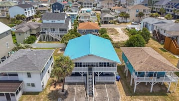 A coastal residential area with houses, a prominent blue-roofed building, and a sandy beach.