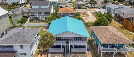 A coastal residential area with houses, a prominent blue-roofed building, and a sandy beach.