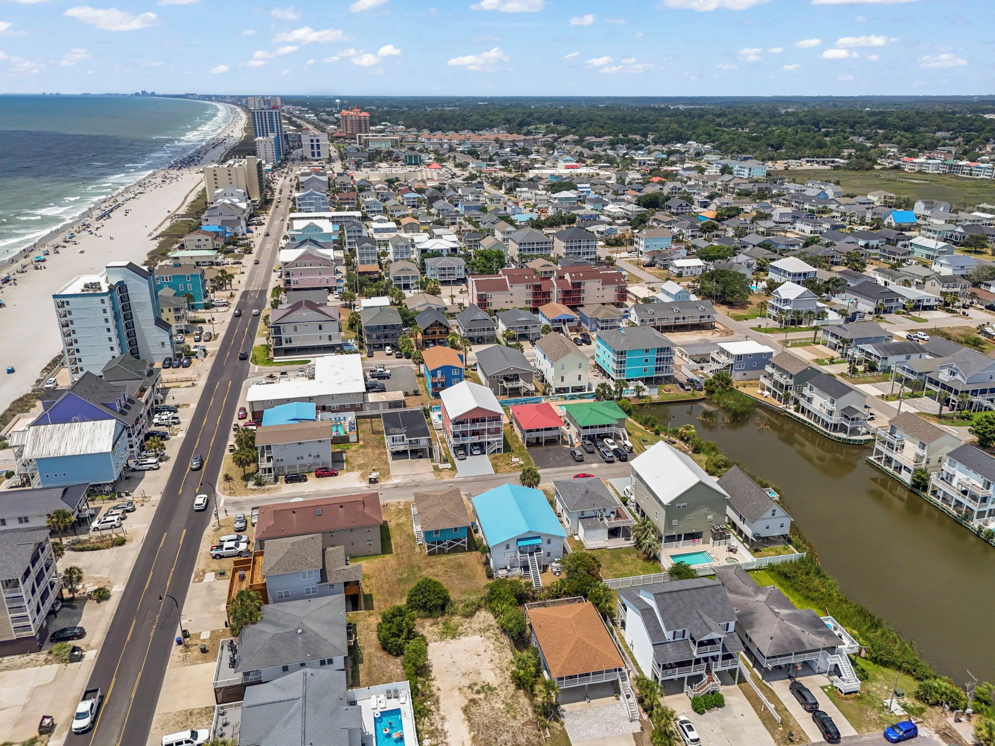 Vista aérea de una zona residencial costera con casas, una playa y una carretera.