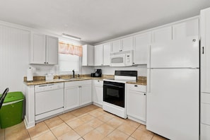 A kitchen with white cabinets, a microwave, a stove, and a refrigerator.
