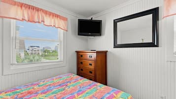 A bedroom with a bed, a dresser, a television, and a mirror.