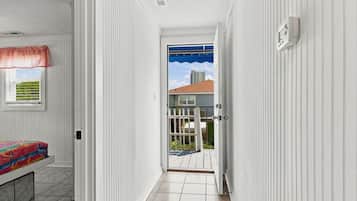 Un couloir comprenant un lit, une fenêtre et une porte donnant sur un espace extérieur.