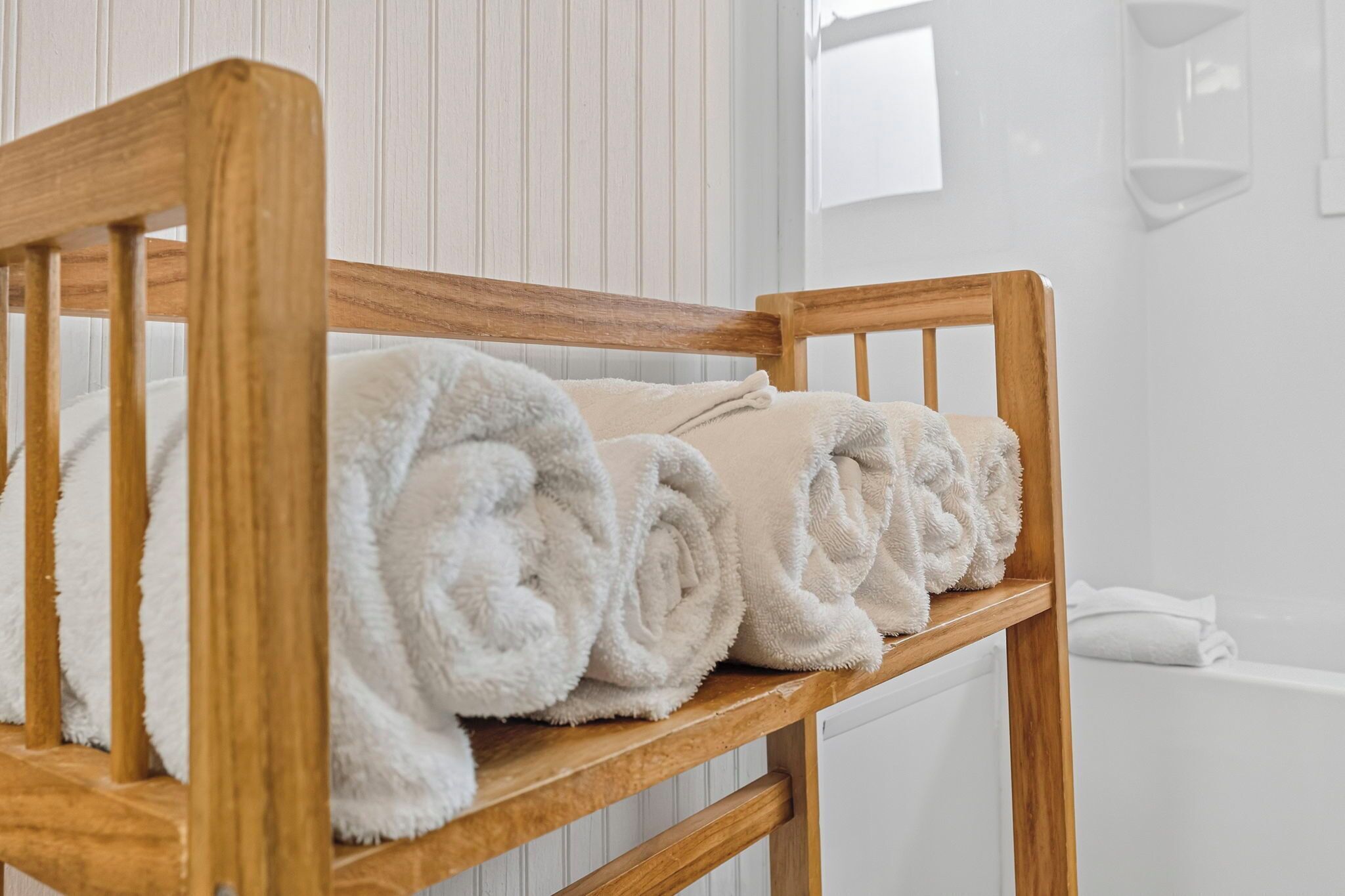 A wooden bench with rolled white towels.