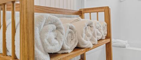 A wooden bench with rolled white towels.